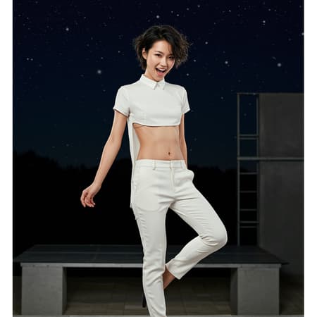A young, slim Asian female supermodel with short tousled black hair poses playfully, donning a stark white, collarless tunic that highlights her flat chest and strong abs. The tunic stops just above her midriff, paired with modernist tapered leg trousers. She kicks one leg up behind her with a sense of carefree joy. The scene captures the essence of the rule of thirds, with the backdrop featuring a Bauhaus-style theater stage set against a minimalist starry night sky. Soft natural lighting gently accentuates her features, adding a serene glow to the overall composition.