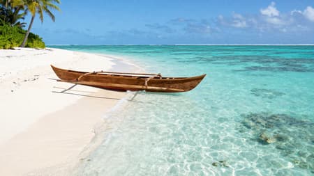 Cinematic Shot Of A Remote Cinematic shot of a remote Polynesian island beach, pristine white sand curving along the shoreline, a single wooden outrigger canoe resting at the water’s edge, crystal-clear turquoise water revealing coral and rippled sand beneath the surface, gentle waves, palm trees leaning toward the sea, bright tropical sunlight, ultra-clear atmosphere, natural colors, serene and untouched mood, high realism