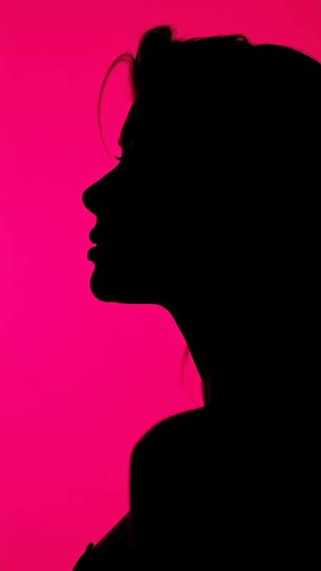 Photorealistic portrait capturing the contrast of a profile silhouette of a woman against a vivid hot pink background, utilizing a camera setup with a large aperture to focus sharply on the silhouette's edge, maintaining vibrant color richness with low ISO for a smooth, grain-free finish, UHD quality, aspect ratio 9:16, subtle creative alterations for artistic flair, raw style with a touch of elegance.