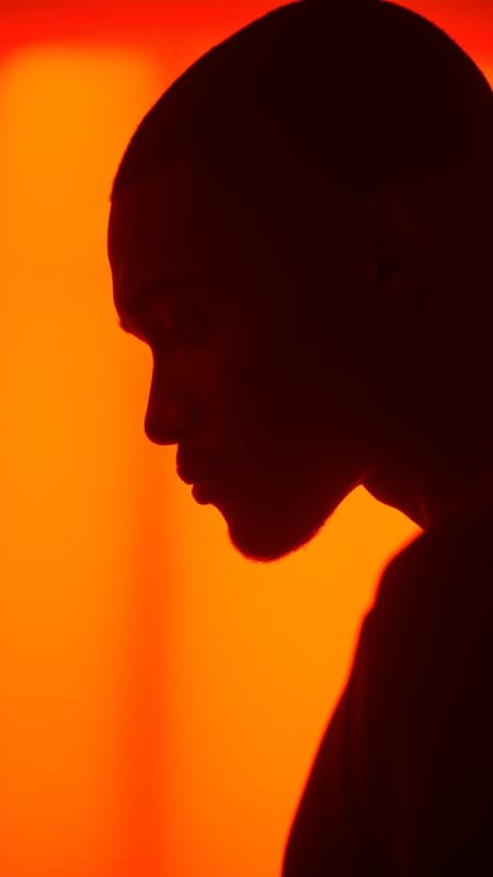 Photography, vivid portrait of contrast capturing the profile silhouette of a black man against a luminous orange background, visualized with a camera setup that emulates a large aperture to focus intensely on the silhouette's contours, maintaining color richness with a low ISO to eliminate grain, photorealistic, UHD, aspect ratio 9:16, infused with a raw and authentic style, slight creative enhancements to highlight the dynamic interplay between light and shadow. Photography, vivid portrait of contrast capturing the profile silhouette of a black man against a luminous orange background, visualized with a camera setup that emulates a large aperture to focus intensely on the silhouette's contours, maintaining color richness with a low ISO to eliminate grain, photorealistic, UHD, aspect ratio 9:16, infused with a raw and authentic style, slight creative enhancements to highlight the dynamic interplay between light and shadow.